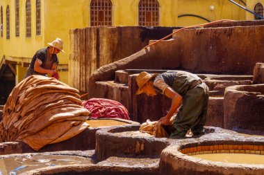 Fes, Fas - 31 Mart 2023: Deri tabakhanesi sahnesi, işçiler ve çeşitli renklerle dolu taş varilleri. Fas 'tan.