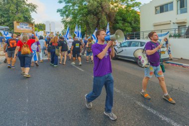Hayfa, İsrail - 17 Ağustos 2024: İnsanlar, hükümete karşı çeşitli tabelalar ve bayraklarla birlikte yeni seçimler çağrısında bulunan bir protesto yürüyüşüne katılıyor. Hayfa, İsrail