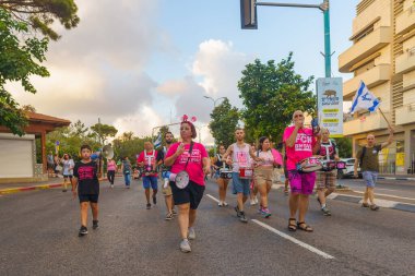 Hayfa, İsrail - 24 Ağustos 2024: İnsanlar, hükümete karşı çeşitli işaret ve bayraklarla yeni seçimler çağrısında bulunan bir protesto yürüyüşüne (pembe grup) katılıyor. Hayfa, İsrail