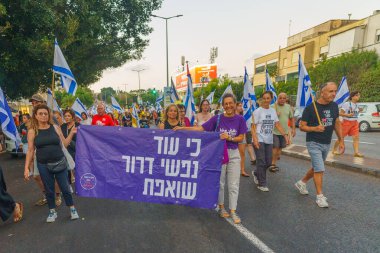 Hayfa, İsrail - 24 Ağustos 2024: İnsanlar, hükümete karşı çeşitli işaret ve bayraklarla yeni seçimler çağrısında bulunan bir protesto yürüyüşüne (zihinsel sağlık grubu) katılıyor. Hayfa, İsrail