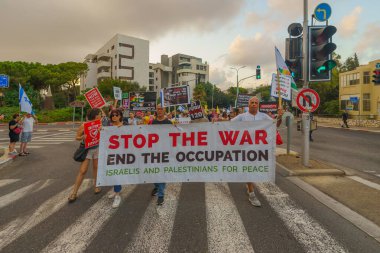 Hayfa, İsrail - 31 Ağustos 2024: Halk, hükümete karşı çeşitli işaret ve bayraklarla yeni seçimler çağrısında bulunan bir protesto yürüyüşüne (barış eylemcileri grubu) katıldı. Hayfa, İsrail