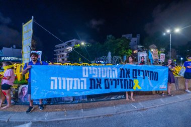 Hayfa, İsrail - 3 Eylül 2024: Rehine Romi Gonen 'in arkadaşlarıyla birlikte İsrail, Hayfa' da rehine anlaşması çağrısında bulunan imzalı ve bayraklı insanların sahnesi