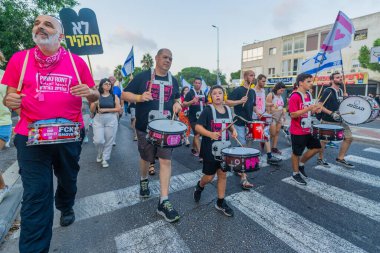 Hayfa, İsrail - 07 Eylül 2024: İnsanlar, hükümete karşı çeşitli işaret ve bayraklarla yeni seçimler çağrısında bulunan bir protesto yürüyüşüne (pembe grup) katılıyor. Hayfa, İsrail