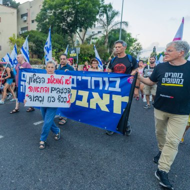 Hayfa, İsrail - 07 Eylül 2024: İnsanlar hükümete karşı çeşitli işaret ve bayraklarla yeni seçimler çağrısında bulunan bir protesto yürüyüşüne (akademi grubu) katılıyor. Hayfa, İsrail