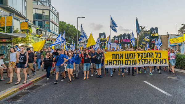 Haifa, Israel - September 07, 2024: Scene of a protest march, against the government, calling for new elections, with people taking part, various signs and flags. Haifa, Israel