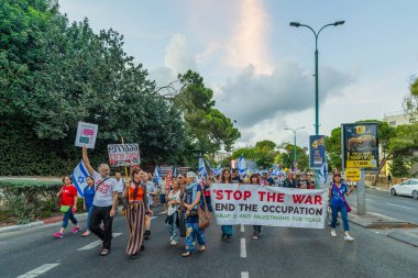Hayfa, İsrail - 21 Eylül 2024: İnsanlar çeşitli işaret ve bayraklarla bir protesto yürüyüşüne katılarak yeni seçimler ve rehine anlaşması çağrısında bulundu. Hayfa, İsrail