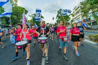 Hayfa, İsrail - 21 Eylül 2024: İnsanlar çeşitli işaret ve bayraklarla yeni seçimler ve rehine anlaşması çağrısında bulunan bir protesto yürüyüşüne (pembe grup) katılıyor. Hayfa, İsrail