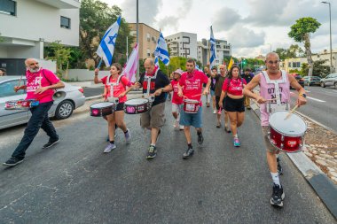 Hayfa, İsrail - 21 Eylül 2024: İnsanlar çeşitli işaret ve bayraklarla yeni seçimler ve rehine anlaşması çağrısında bulunan bir protesto yürüyüşüne (pembe grup) katılıyor. Hayfa, İsrail