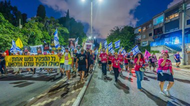 Hayfa, İsrail - 21 Eylül 2024: Hükümete karşı bir protesto yürüyüşü sahnesi, yeni seçimler ve insanların yer aldığı bir rehine anlaşması, çeşitli tabelalar ve bayraklar. Hayfa, İsrail