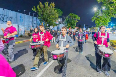 Hayfa, İsrail - 07 Aralık 2024: İnsanlar çeşitli işaret ve bayraklarla yeni seçimler ve rehine anlaşması çağrısında bulunan bir protesto yürüyüşüne (pembe grup) katılıyor. Hayfa, İsrail