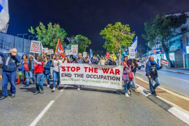 Hayfa, İsrail - 07 Aralık 2024: İnsanlar çeşitli işaret ve bayraklarla bir protesto yürüyüşüne katılarak yeni seçimler ve rehine anlaşması çağrısında bulundular. Hayfa, İsrail