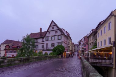 Bamberg, Almanya - 07 Ekim 2024: Obere Brucke 'nin (üst köprü) çeşitli bina, yerli ve ziyaretçilerle birlikte Bamberg, Bavyera, Almanya' da günbatımı manzarası