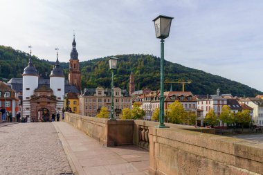 Heidelberg, Almanya - 13 Ekim 2024: Heidelberg, Baden-Wurttemberg, Almanya 'da bulunan Karl Theodor Köprüsü veya Old Stone Köprüsü' nün kulesi, yerlileri ve ziyaretçileri ile birlikte manzarası