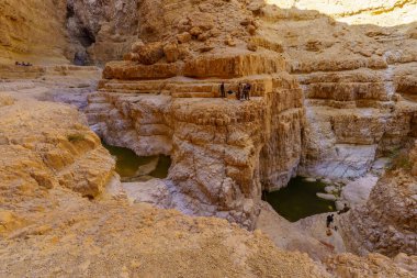 Masada, İsrail - 19 Ocak 2024: Kış su birikintileri ve iniş pratiği yapan ziyaretçilerle birlikte çöl manzarası manzarası. Ölü Deniz Kıyısı, Judaean Çölü, Güney İsrail