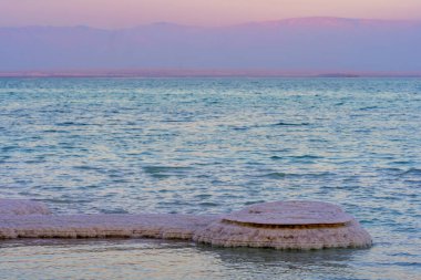 Ölü Deniz kıyısındaki tuz oluşumlarının günbatımı manzarası. Ein Bokek tatil köyü, Judaean Çölü, Güney İsrail
