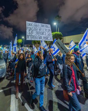 Hayfa, İsrail - 21 Aralık 2024: İnsanlar çeşitli tabelalar ve bayraklarla birlikte protesto yürüyüşüne katılarak yeni seçimler ve rehine anlaşması çağrısında bulundular. Hayfa, İsrail