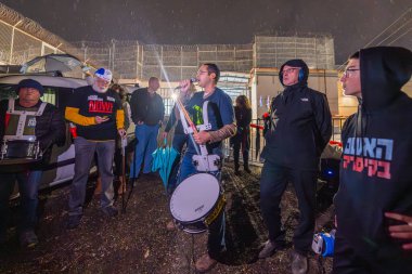 Kishon, Israel - December 23, 2024: People are protesting in a rainy evening, near the Kishon detention center in support of activist arrested after firing Naval Flares. Kishon, Israel clipart