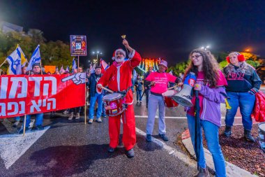 Hayfa, İsrail - 28 Aralık 2024: İnsanlar (Noel Baba ve Hanuka Menorah gibi giyinmiş bir adamla birlikte) yeni seçimler ve bir rehine anlaşması çağrısında bulunarak protesto yürüyüşüne katılıyor. Hayfa, İsrail