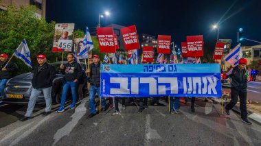 Hayfa, İsrail - 4 Ocak 2025: Çeşitli tabelaları ve bayrakları olan insanlar yeni seçim ve rehine anlaşması çağrısında bulunan bir protesto mitingine katıldılar. Hayfa, İsrail