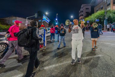Hayfa, İsrail - 4 Ocak 2025: Çeşitli tabelaları ve bayrakları olan insanlar yeni seçim ve rehine anlaşması çağrısında bulunan bir protesto mitingine katıldılar. Hayfa, İsrail