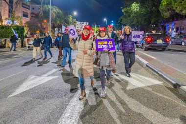 Hayfa, İsrail - 4 Ocak 2025: Çeşitli tabelaları ve bayrakları olan insanlar yeni seçim ve rehine anlaşması çağrısında bulunan bir protesto mitingine katıldılar. Hayfa, İsrail