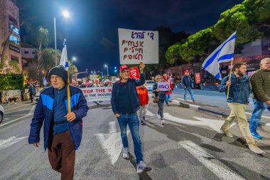 Hayfa, İsrail - 4 Ocak 2025: Çeşitli tabelaları ve bayrakları olan insanlar yeni seçim ve rehine anlaşması çağrısında bulunan bir protesto mitingine katıldılar. Hayfa, İsrail