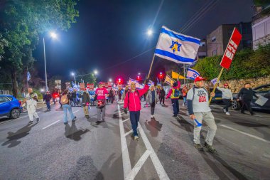 Hayfa, İsrail - 4 Ocak 2025: İnsanlar çeşitli tabelalar ve bayraklarla bir protesto yürüyüşüne katılarak yeni seçimler ve rehine anlaşması çağrısında bulundular. Hayfa, İsrail