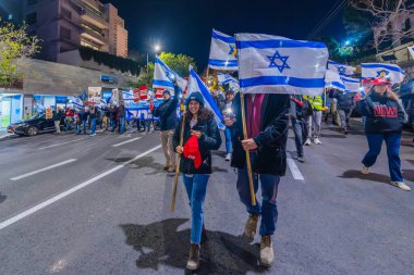 Hayfa, İsrail - 4 Ocak 2025: Çeşitli tabelaları ve bayrakları olan insanlar yeni seçim ve rehine anlaşması çağrısında bulunan bir protesto mitingine katıldılar. Hayfa, İsrail