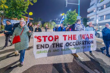 Hayfa, İsrail - 11 Ocak 2025: İnsanlar çeşitli işaret ve bayraklarla bir protesto yürüyüşüne katılarak savaşın sona ermesi, rehine anlaşması ve yeni seçimler çağrısında bulundular. Hayfa, İsrail