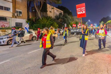 Hayfa, İsrail - 11 Ocak 2025: Çeşitli tabelaları ve bayrakları olan insanlar, savaşın sona ermesi, rehine anlaşması ve yeni seçimler için düzenlenen protesto mitingine katıldılar. Hayfa, İsrail