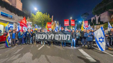 Hayfa, İsrail - 11 Ocak 2025: Çeşitli tabelaları ve bayrakları olan insanlar, savaşın sona ermesi, rehine anlaşması ve yeni seçimler için düzenlenen protesto mitingine katıldılar. Hayfa, İsrail