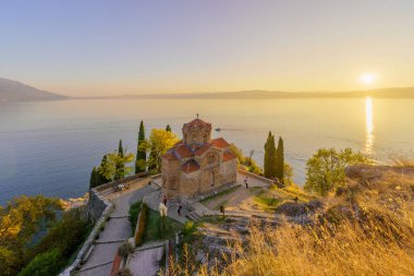 Ohri, Kuzey Makedonya - 03 Ekim 2023: Eski Makedonya 'nın Ohri kentindeki Aziz John Kilisesi' nin ziyaretçilerle birlikte gün batımı manzarası