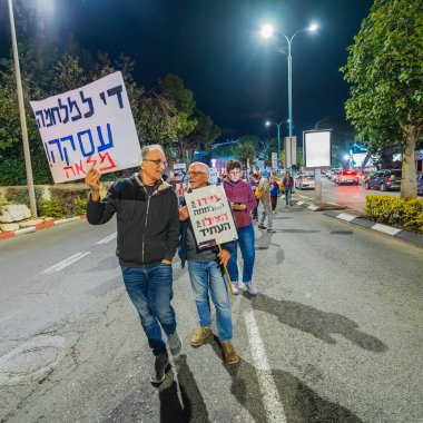 Hayfa, İsrail - 25 Ocak 2025: İnsanlar çeşitli işaret ve bayraklarla, savaşın sona ermesi, rehine anlaşmasının tamamlanması ve yeni seçimler çağrısında bulunan bir protesto yürüyüşüne (barış eylemcileri grubu) katılıyor. Hayfa, İsrail