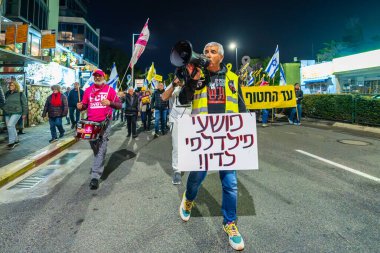 Hayfa, İsrail - 25 Ocak 2025: Çeşitli tabelaları ve bayrakları olan insanlar, savaşın sona ermesi, rehine anlaşmasının tamamlanması ve yeni seçimlerin başlatılması için düzenlenen protesto mitingine katıldılar. Hayfa, İsrail