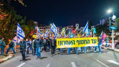 Hayfa, İsrail - 25 Ocak 2025: Çeşitli tabelaları ve bayrakları olan insanlar, savaşın sona ermesi, rehine anlaşmasının tamamlanması ve yeni seçimlerin başlatılması için düzenlenen protesto mitingine katıldılar. Hayfa, İsrail