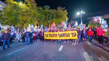 Hayfa, İsrail - 25 Ocak 2025: Çeşitli tabelaları ve bayrakları olan insanlar, savaşın sona ermesi, rehine anlaşmasının tamamlanması ve yeni seçimlerin başlatılması için düzenlenen protesto mitingine katıldılar. Hayfa, İsrail