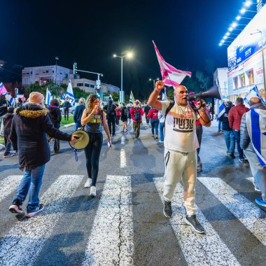 Hayfa, İsrail - 25 Ocak 2025: Çeşitli tabelaları ve bayrakları olan insanlar, savaşın sona ermesi, rehine anlaşmasının tamamlanması ve yeni seçimlerin başlatılması için düzenlenen protesto mitingine katıldılar. Hayfa, İsrail