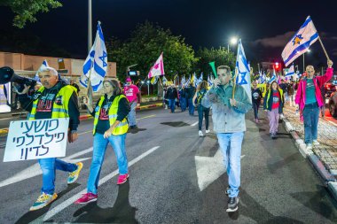 Hayfa, İsrail - 25 Ocak 2025: Çeşitli tabelaları ve bayrakları olan insanlar, savaşın sona ermesi, rehine anlaşmasının tamamlanması ve yeni seçimlerin başlatılması için düzenlenen protesto mitingine katıldılar. Hayfa, İsrail