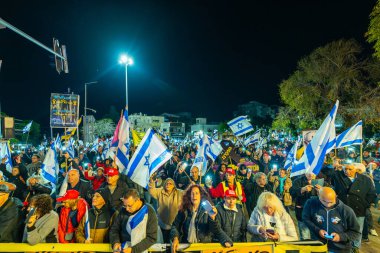 Hayfa, İsrail - 25 Ocak 2025: Çeşitli tabela ve bayraklara sahip bir grup insan, savaşın sona ermesi, rehine anlaşmasının tamamlanması ve yeni seçimler için düzenlenen protesto mitingine katıldı. Hayfa, İsrail