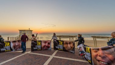 Hayfa, İsrail - 29 Ocak 2025: Rehine posterleri tutan insanlar zinciri, metin: Gün batımında beni geride bırakmayın, Hayfa, İsrail sahilinde