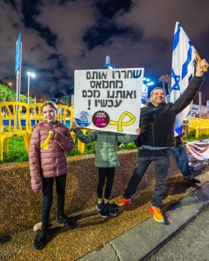 Hayfa, İsrail - 08 Şubat 2025: Çeşitli tabela ve bayraklara sahip insanlar savaşın sona ermesi, rehine anlaşmasının tamamlanması ve yeni seçimler için düzenlenen protesto mitingine katıldılar. Hayfa, İsrail