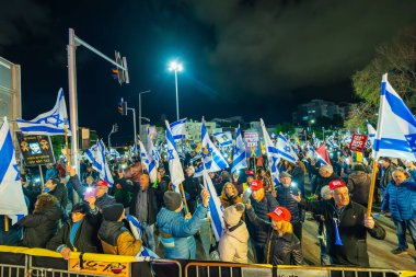 Hayfa, İsrail - 08 Şubat 2025: Çeşitli tabela ve bayraklara sahip bir grup insan, savaşın sona ermesi, rehine anlaşmasının tamamlanması ve yeni seçimler için düzenlenen protesto mitingine katıldı. Hayfa, İsrail