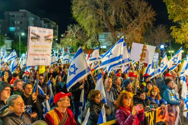 Hayfa, İsrail - 08 Şubat 2025: Çeşitli tabela ve bayraklara sahip bir grup insan, savaşın sona ermesi, rehine anlaşmasının tamamlanması ve yeni seçimler için düzenlenen protesto mitingine katıldı. Hayfa, İsrail