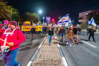 Hayfa, İsrail - 15 Şubat 2025: Çeşitli tabela ve bayraklara sahip insanlar savaşın sona ermesi, rehine anlaşmasının tamamlanması ve yeni seçimler için düzenlenen protesto mitingine katıldılar. Hayfa, İsrail