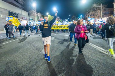 Hayfa, İsrail - 15 Şubat 2025: Çeşitli tabela ve bayraklara sahip insanlar savaşın sona ermesi, rehine anlaşmasının tamamlanması ve yeni seçimler için düzenlenen protesto mitingine katıldılar. Hayfa, İsrail