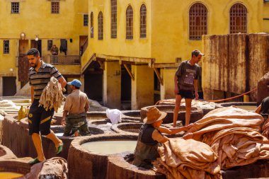 Fes, Fas - 31 Mart 2023: Deri tabakhanesi sahnesi, işçiler ve çeşitli renklerle dolu taş varilleri. Fas 'tan.