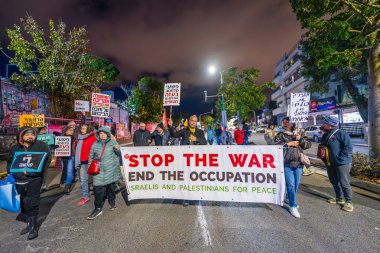 Hayfa, İsrail - 22 Şubat 2025: İnsanlar çeşitli işaret ve bayraklarla bir protesto yürüyüşüne katılıyor, savaşın sona ermesi ve rehine anlaşmasının tamamlanması çağrısında bulunuyorlar. Hayfa, İsrail