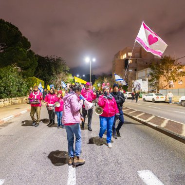 Hayfa, İsrail - 22 Şubat 2025: İnsanlar savaşın sona ermesi, rehine anlaşmasının tamamlanması ve yeni seçimler çağrısında bulunan bir protesto yürüyüşüne katılıyor. Hayfa, İsrail