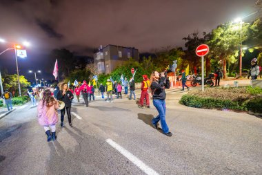 Hayfa, İsrail - 22 Şubat 2025: Çeşitli tabela ve bayraklara sahip insanlar savaşın sona ermesi, rehine anlaşmasının tamamlanması ve yeni seçimler için düzenlenen protesto mitingine katıldılar. Hayfa, İsrail
