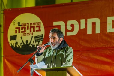 Haifa, Israel - February 22, 2025: Boaz Zalmanovich whos 85 years old father was kidnapped, speaks to the crowd, part of a protest rally. Haifa, Israel clipart